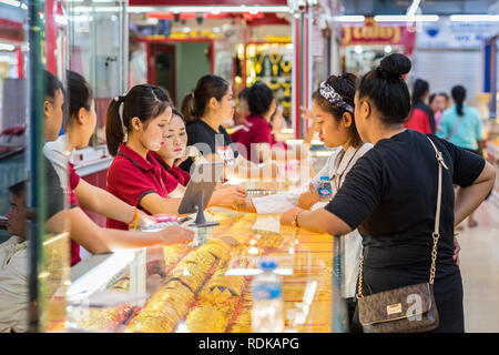 Vientiane, Laos - Agosto 9, 2018: giovane donna cerca su un bracciale oro in presenza del suo amico e tre donne i venditori a Talat Sao Mall. Foto Stock