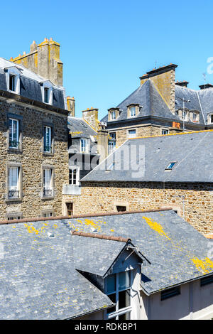 Vista sopra i tetti di ardesia di edifici residenziali di varie altezze nella città murata di Saint Malo in Bretagna, Francia, sotto un cielo blu. Foto Stock