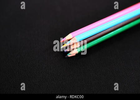 Foto di legno quattro matite colorate. Isolato su sfondo nero. Foto Stock