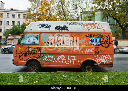 Vecchio rotto orange van completamente riddled con graffiti Foto Stock