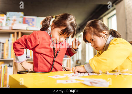 Carino sunny bambini indossare maglioni luminoso giocare insieme Foto Stock