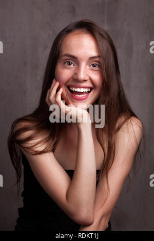 Sorridente giovane donna su grigio scuro dello sfondo grunge Foto Stock