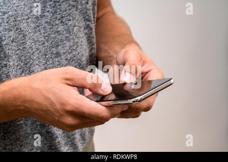 Immagine ravvicinata di uomo di mani smart telefono cellulare con la copia in bianco sullo schermo dello spazio per il tuo testo. Studente la digitazione di un messaggio sul telefono cellulare mentre sitti Foto Stock