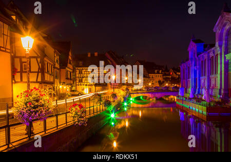 Vecchie case colorate illuminato, piccolo fiume, acqua riflessione a notte in primavera, Colmar, Francia. Foto Stock