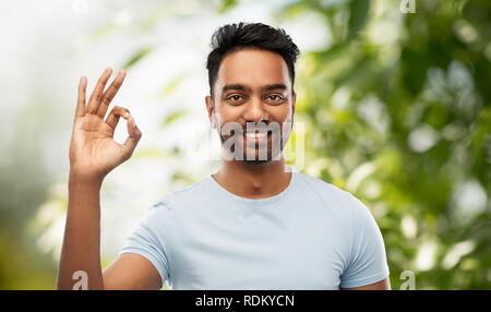 Felice l'uomo indiano in t-shirt mostra segno OK con la mano Foto Stock