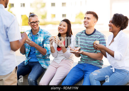 Gli amici di mangiare pizza e tramezzini in posizione di parcheggio Foto Stock