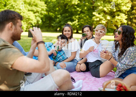Amici con bevande a fotografare al picnic estivo Foto Stock