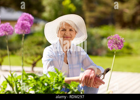 Donna senior con giardino potatore e fiori Foto Stock