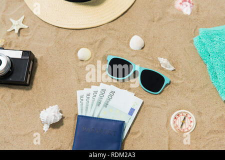 Denaro nel passaporto, sfumature e hat sulla spiaggia di sabbia Foto Stock