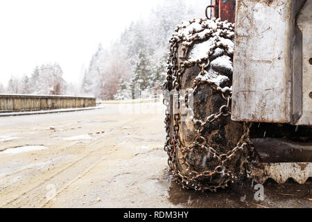 Primo piano delle catene da neve montate su una vettura nevoso ruota. Pneumatici montati con catene da neve in inverno nevoso giorno. Foto Stock