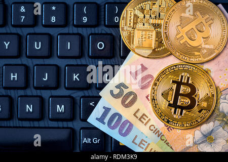 Bitcoins metallico e il rumeno denaro (Ron, Nuovo Lei) sulla tastiera. Concetto di nuovo denaro virtuale moneta. Foto Stock