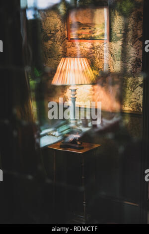 Vista attraverso il sipario del blue vintage lampada da tavolo con crema paralume plissettato. Foto Stock