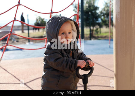 Carino Baby Boy giocando con una scooter 3 ruote su un parco giochi. Vista ravvicinata ritratto Foto Stock