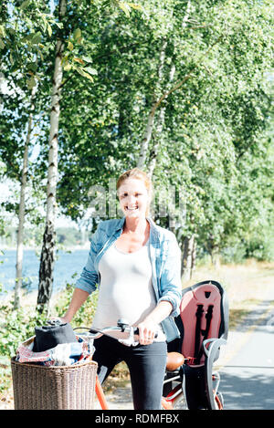 Sorridente donna incinta con noleggio biciclette Foto Stock