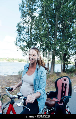 Sorridente donna incinta con noleggio biciclette Foto Stock