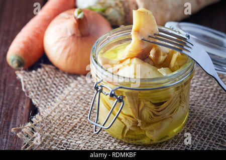 Decapati carciofi marinati in un vasetto di vetro sul tavolo Foto Stock