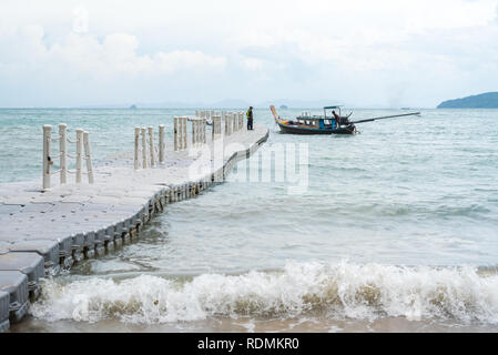 Plastica molo pontone galleggiante nel mare con un Thai imbarcazione attraccata alla sua estremità. Bassa stagione (luglio) al Pai Plong Spiaggia Ao Nang, Krabi, Thailandia. Foto Stock