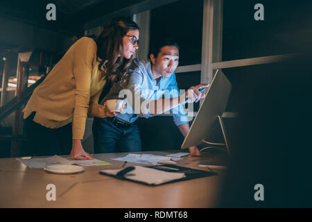 uomo d'affari e donna che discutono di lavorare insieme guardando un computer a tarda notte. colleghi d'affari che lavorano seriamente a tarda notte Foto Stock