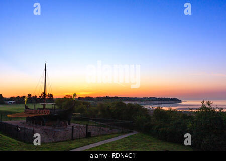 Alba cielo di Ramsgate visto da Pegwell Bay della Nave Vichinga. Blu cielo con sottile fascia di colore arancione sull'orizzonte. Chalk cliffs e sulla baia con la bassa marea. Foto Stock