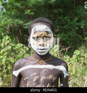 Surma ragazzo con trattamenti per il viso e per il corpo della pittura, Kibish, Omo River Valley, Etiopia, Africa Foto Stock