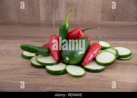 Fresco di zucchine tagliate e jalapeno verde e peperoncino rosso su uno sfondo di legno. Foto Stock