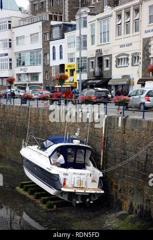 Barca che giace a secco di marina a bassa marea, porto principale, St. Peter Port Guernsey, Isole del Canale, Europa Foto Stock