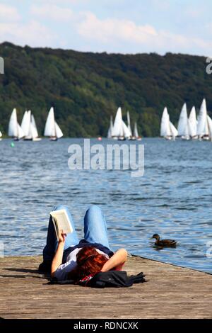 La donna la lettura di un libro sulla riva del lago, 51st Essen la settimana della vela sul lago di Baldeney, Essen, Renania settentrionale-Vestfalia Foto Stock