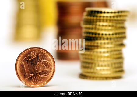 Close up di un centesimo di Euro e pile di monete su sfondo bianco Foto Stock