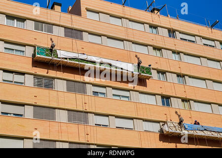 I lavoratori sulla impalcatura esterna ascensore per riparare l'edificio Foto Stock