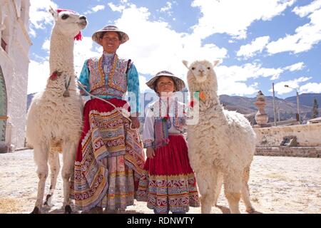 Donna e bambina con lama e alpaca in Maca vicino Canyon del Colca, Perù, Sud America Foto Stock