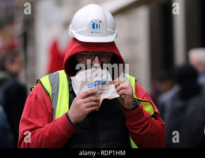 Costruttori di mangiare cibo Greggs camminando lungo Foto Stock