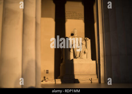 Lincoln Memorial Abraham Lincoln Statue Washington DC // WASHINGTON DC, Stati Uniti - al Lincoln Memorial di Washington DC di prima mattina, all'estremità occidentale del National Mall, commemora il 16° presidente degli Stati Uniti, Abraham Lincoln. Questa foto è stata scattata intorno al solstizio di primavera. Con il sole che sorge direttamente a est, la luce splende brevemente direttamente sull'imponente statua di Lincoln che si trova in profondità all'interno dell'edificio. Foto Stock