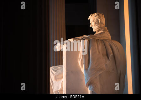 Statua del Lincoln Memorial Washington DC // WASHINGTON DC, Stati Uniti - la mattina presto al Lincoln Memorial di Washington DC, situato all'estremità occidentale del National Mall, commemora il 16° presidente degli Stati Uniti, Abraham Lincoln. Questa foto è stata scattata intorno al solstizio di primavera. Con il sole che sorge direttamente a est, la luce splende brevemente direttamente sull'imponente statua di Lincoln che si trova in profondità all'interno dell'edificio. Foto Stock