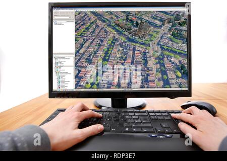 Persona seduta a un computer funzionante con Google Street View, lo schermo mostra un'immagine di parte del centro della città di Amsterdam Foto Stock