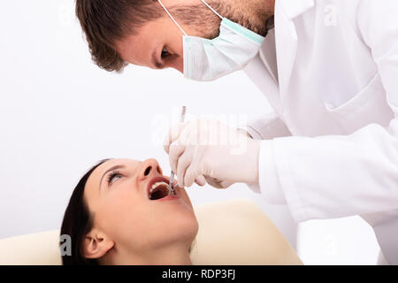 Close-up di dentista esaminando giovane donna i denti in clinica Foto Stock