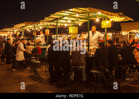 Fornitore serve la gente per mangiare in un mercato notturno di stallo alimentare Foto Stock