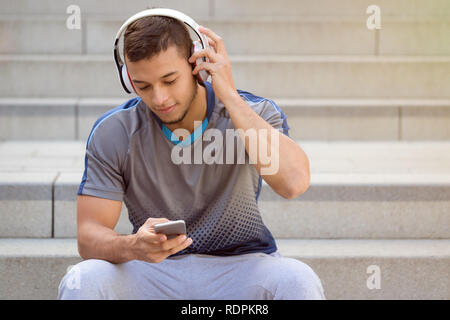 Ascolto di musica latina giovane uomo ascoltare le cuffie copyspace copia spazio all'aperto Foto Stock