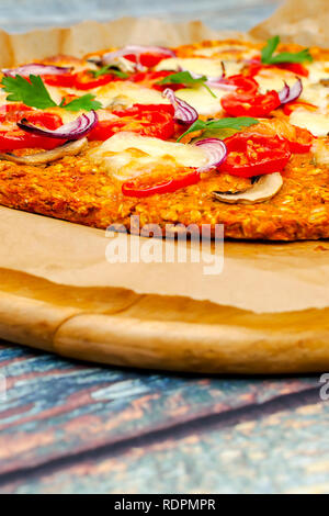 Pizza con blat della patata dolce e semi di avena, guarnita con funghi, cipolle, mozzarella e pomodoro ciliegino Foto Stock