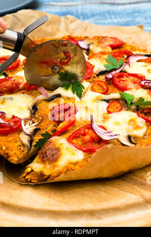 Pizza con blat della patata dolce e semi di avena, guarnita con funghi, cipolle, mozzarella e pomodoro ciliegino Foto Stock