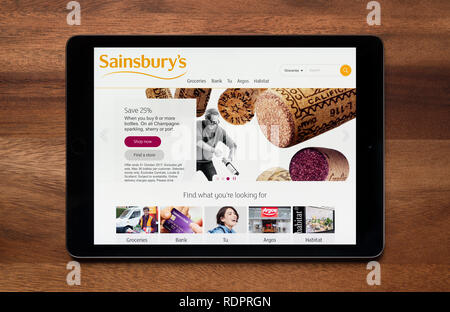 Il sito web di Sainsbury's è visto su un tablet iPad, il quale è appoggiato su un tavolo di legno (solo uso editoriale). Foto Stock