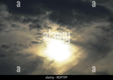 Sun dietro dark cloud simile a occhio il cielo Foto Stock