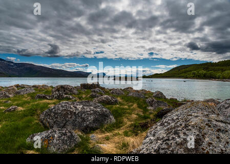 Primavera vista delle isole montagnose intersecata dall'oceano sotto una tempesta cielo pesante. Norvegia Lofoten, Hinnoya. Foto Stock