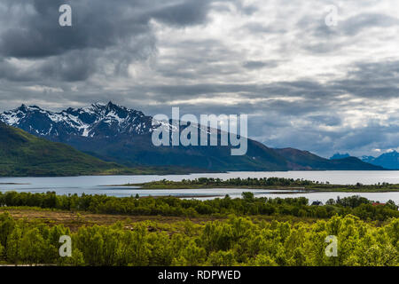 Primavera vista delle isole montagnose intersecata dall'oceano sotto una tempesta cielo pesante. Norvegia Lofoten, Hinnoya. Foto Stock