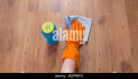 Una donna mano utilizzando stracci blu strofinare il pavimento in legno. Foto Stock