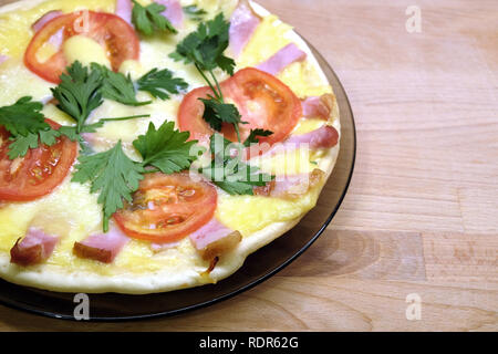 Frammento della piastra preparata con gustosa pizza con pomodori, pancetta e formaggio su sfondo di legno vista superiore Foto Stock