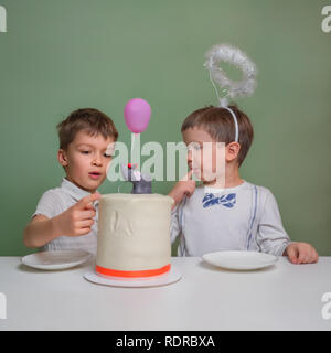 Tastying deliziosa torta. Bambini leccare la torta di compleanno crema. Tabella di dolci per i bambini. Torta di compleanno Funny felici i bambini. Fratelli maggiori celebrazione o Foto Stock