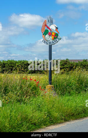 Ingham Village segno. Strada orlo. ​Norfolk. East Anglia, Inghilterra, Regno Unito. ​Midst papaveri e semina di graminacee. Raffiguranti storiche, attuale occupazione agricola e sportivi di temi di interesse locale. Foto Stock