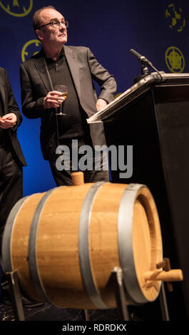 Mainz, Germania. 18 gennaio, 2019. Robert Menasse, scrittore austriaco e vincitore del 2019 Carl Zuckmayer medaglia, stand con un bicchiere di vino davanti ad un 30 litro botte di vino. Il nobile goccia è parte del premio. La medaglia è donato in memoria dello scrittore e drammaturgo che era nato a Nackenheim. Il premio riconosce i meriti per la lingua tedesca ed è presentato annualmente. Credito: Andreas Arnold/dpa/Alamy Live News Foto Stock