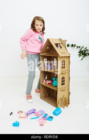 Felice bambina gioca con la casa di bambola e casa di bambola mobili. Funny bel bambino si diverte a Foto Stock