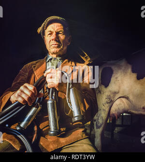 Brecon Beacons,Wales, Regno Unito, novembre 2,1988: un anziano contadino pone con la sua macchina di mungitura con mucche in procinto di essere munte in early morning sun. Foto Stock